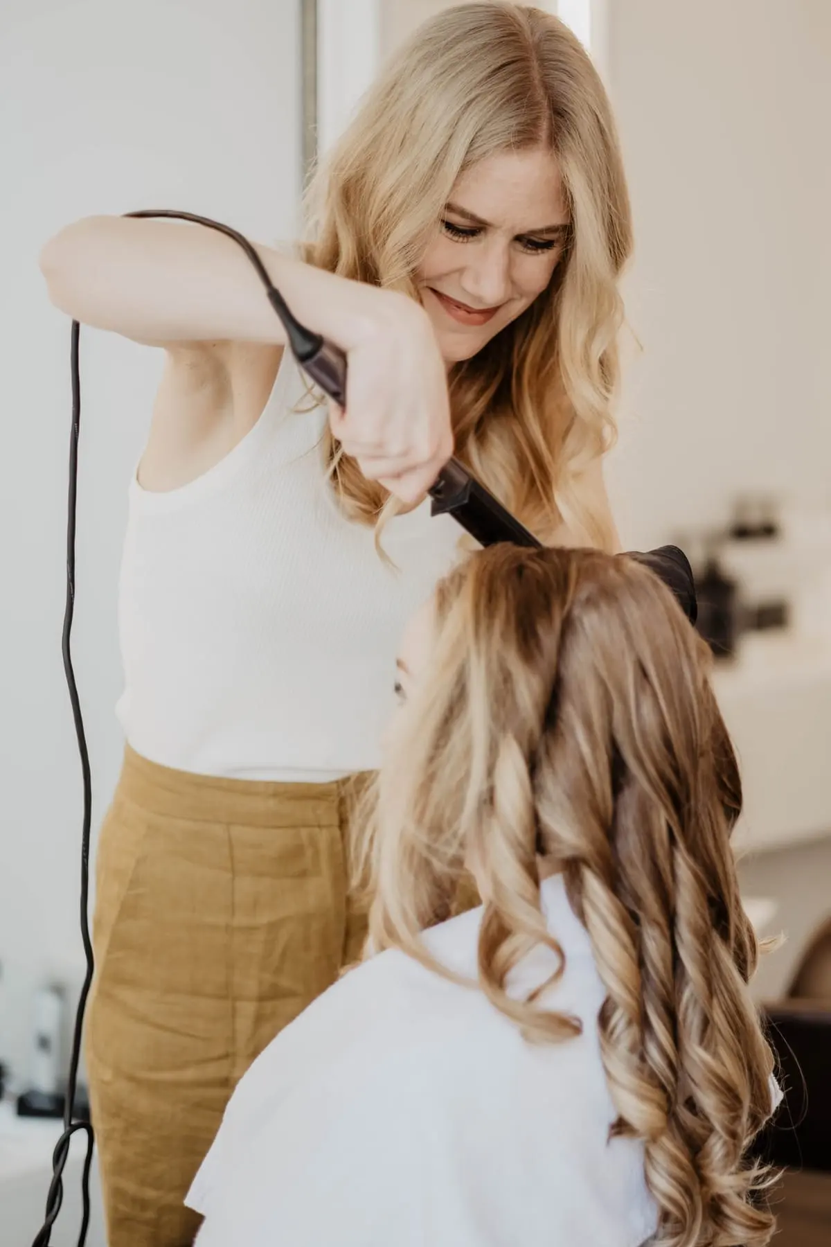 Julia-Valesca Bliedung stylt im Studio das Haar einer Kundin mit dem Lockenstab
