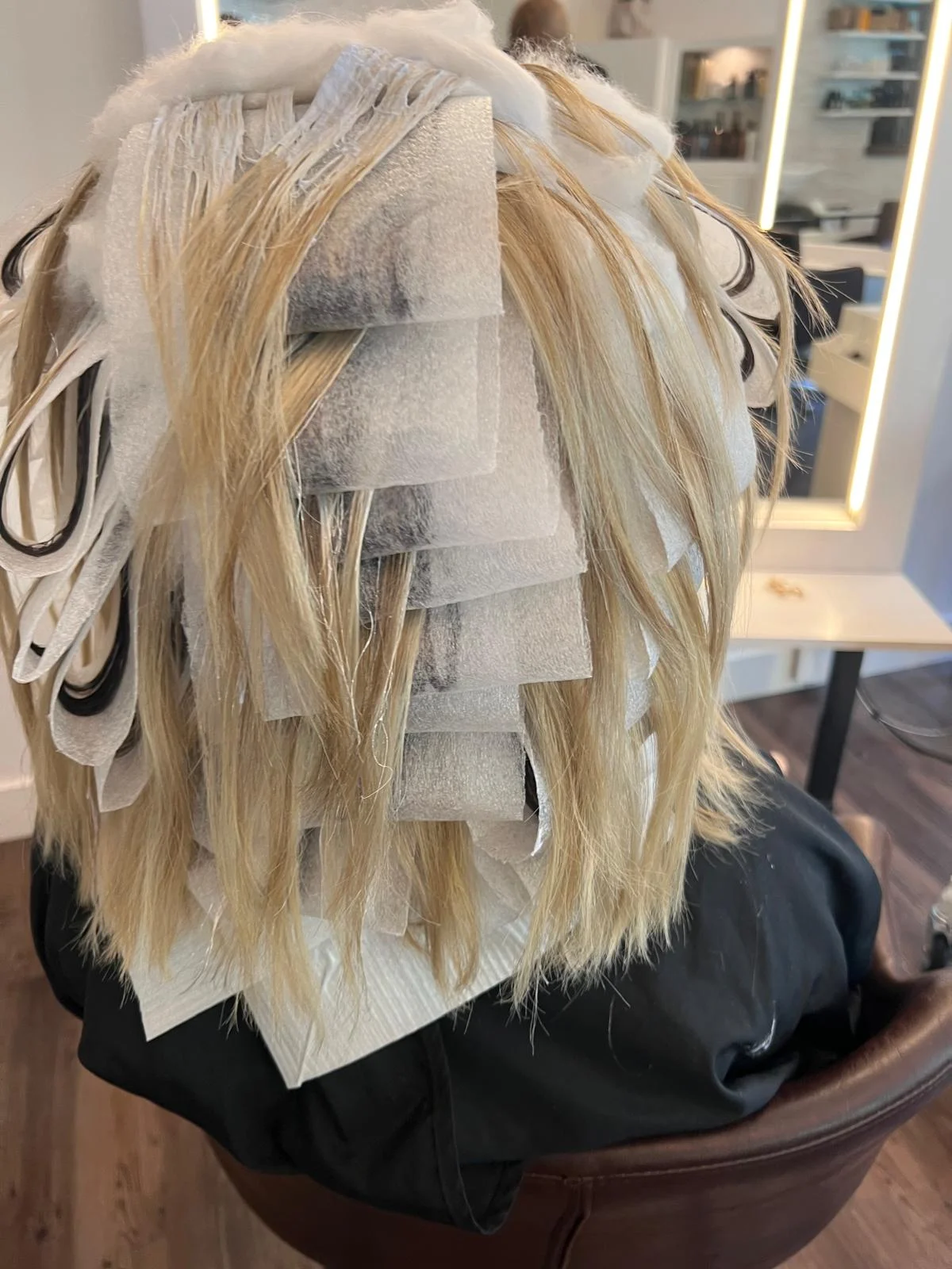Watte-Mèches während der Behandlung: feine blonde Haarsträhnen, mit Aufhellung bestrichen und durch Watte getrennt